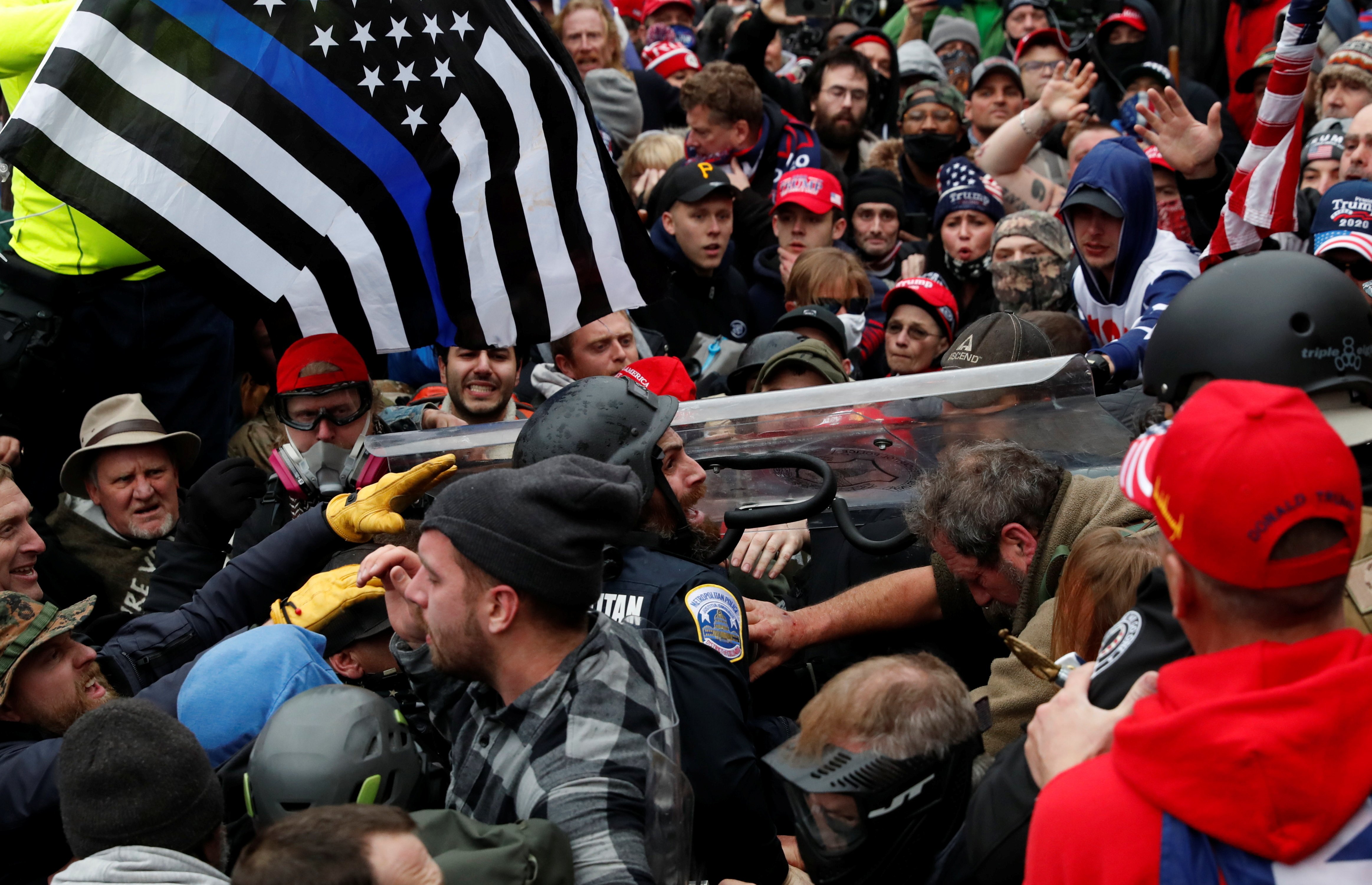 Um policial é arrastado em uma multidão de manifestantes pró-Trump durante um confronto