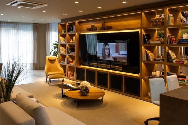 Sala de estar tem como destaque a estante planejada sob medida, cuja TV é o ponto central.