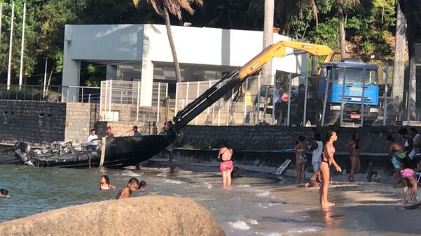 Lancha que pegou fogo é retirada da praia em Vitória