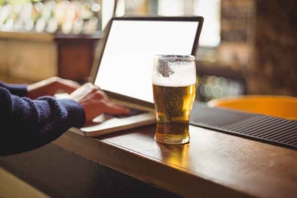 Homem em um bar com um notebook e um copo de cerveja