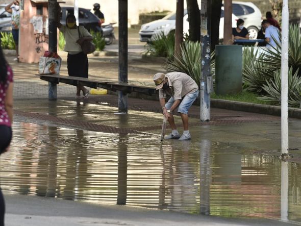 Um dia após a chuva, no bairro Caratoíra, em Vitória, um homem tenta desentupir um bueiro com um pedaço de madeira por Ricardo Medeiros