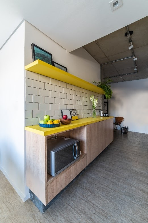 A arquiteta Júlia Guadix optou por usar MDF com folha de fórmica amarela dessa cozinha. Por ser uma área de bancada sem pia, ela não corre o risco de ficar úmida | Projeto: Liv’n Arquitetura |