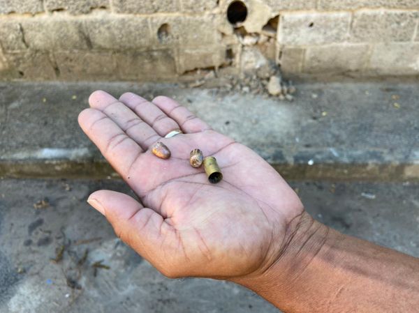 Homem mostra cápsulas encontradas em local de assassinato em Inhanguetá, em Vitória