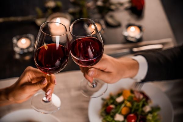 Casal brindando com taças de vinho tinto no Dia dos Namorados