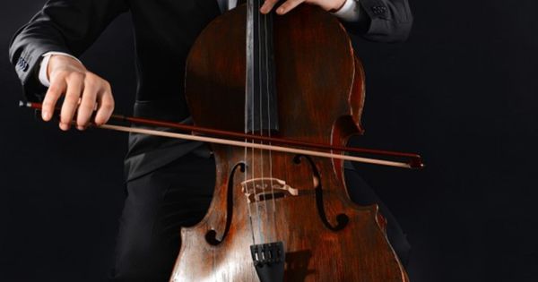 Homem tocando violoncelo em orquestra; música; música clássica, música erudita