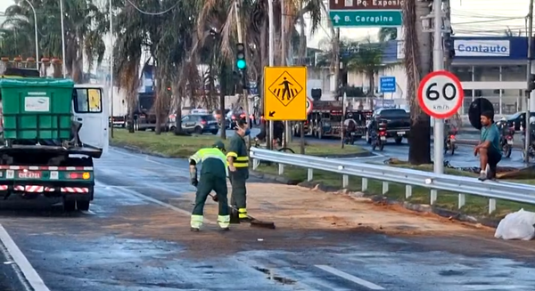 Funcionários fazem a varrição da serragem jogada na pista para retirada do óleo vazado das carretas