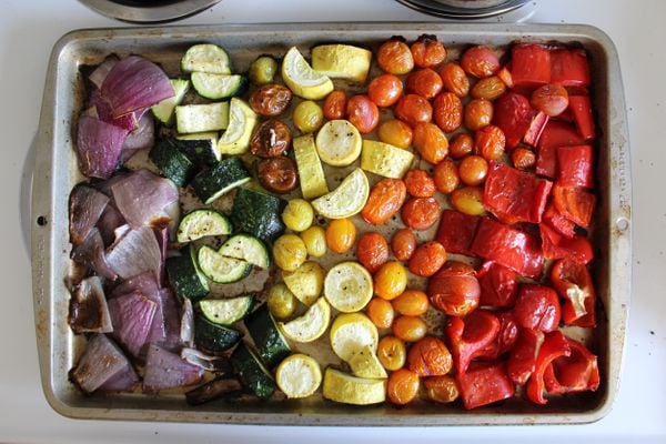 Legumes assados em uma travessa: cebola, abobrinha, tomate e pimentão