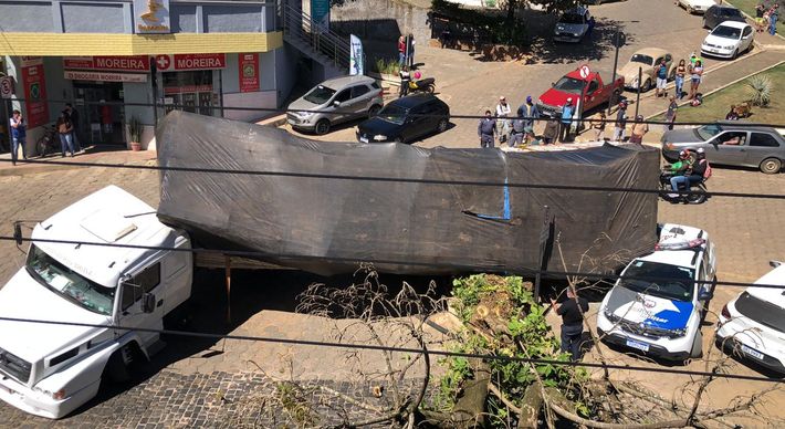 Com a manobra do caminhão, a carga tombou em cima de uma viatura estacionada e uma antiga árvore também veio ao chão. Ninguém ficou ferido no acidente