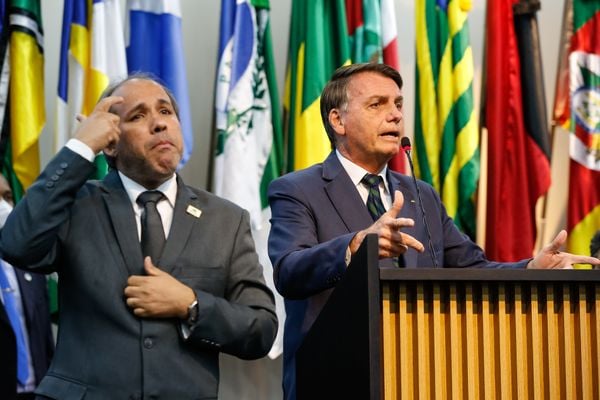 Presidente Jair Bolsonaro discursa, ao microfone. Ao lado dele, o intérprete de Libras