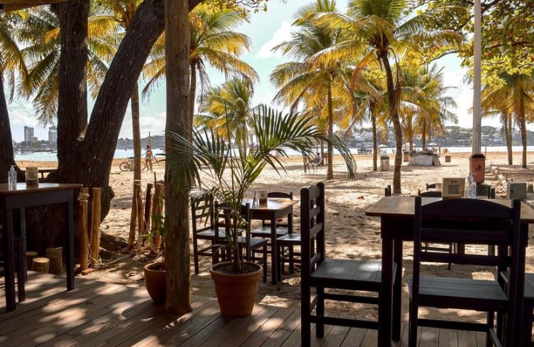 As mesas do café ficam em ambiente aberto e têm vista para a praia da Curva da Jurema