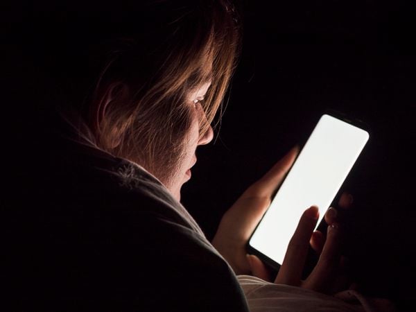 Criança em frente à tela de celular, vício tecnológico, mexer no smartphone