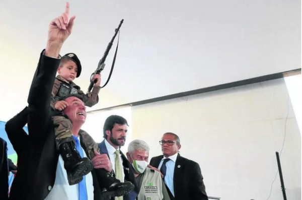 O presidente Jair Bolsonaro posa com criança empunhando uma arma de brinquedo em evento em Belo Horizonte
