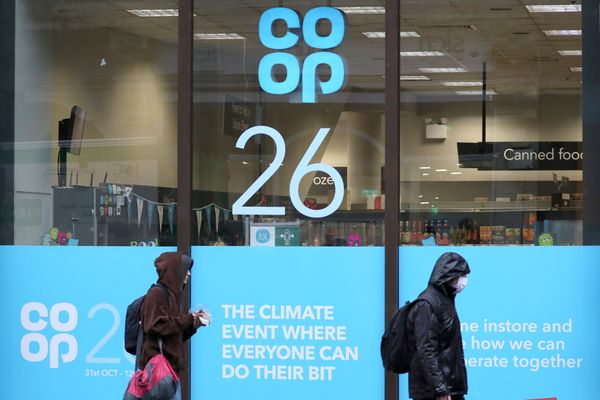 Pedestres passam por uma vitrine no   centro da cidade de Glasgow, na Escócia, com adesivos anunciando a 26ª Conferência Climática das Nações Unidas (COP26), que começa no domingo