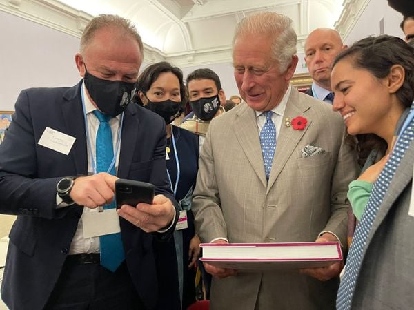 Governador Renato Casagrande mostra, no celular, foto de árvore plantada pelo príncipe Charles em Aracruz ao herdeiro do trono britânico