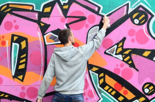 Homem realiza graffiti em muro