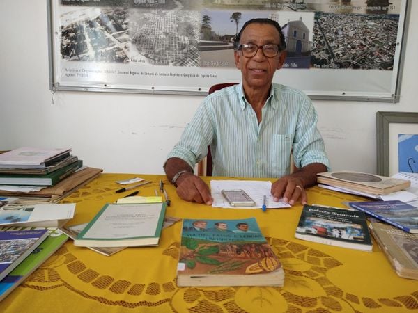 Historiador Reuber Costa rodeado por livros sobre a história de Linhares