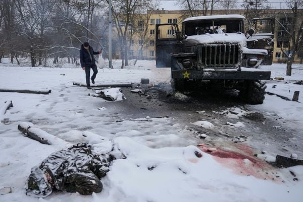 O corpo de um militar coberto de neve ao lado de um veículo militar russo lançador de foguetes destruído nos arredores de Kharkiv, na Ucrânia, nesta sexta-feira (25/02)