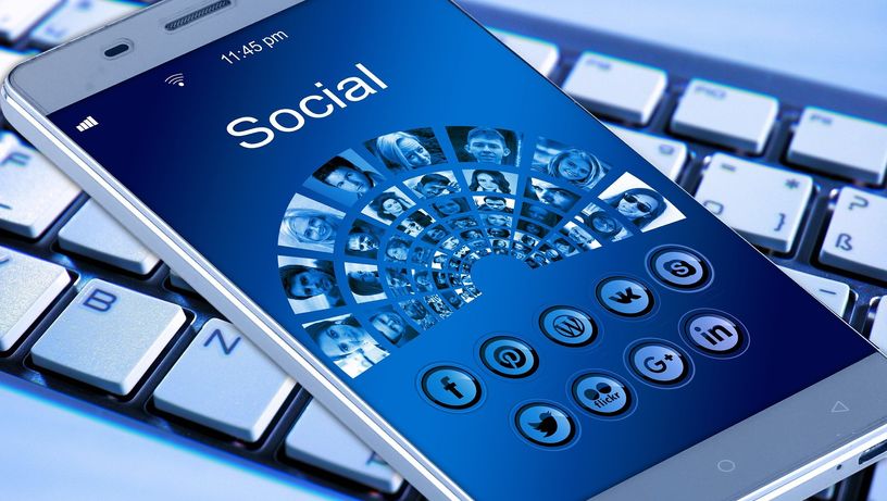 Celular com redes sociais e teclado de computador