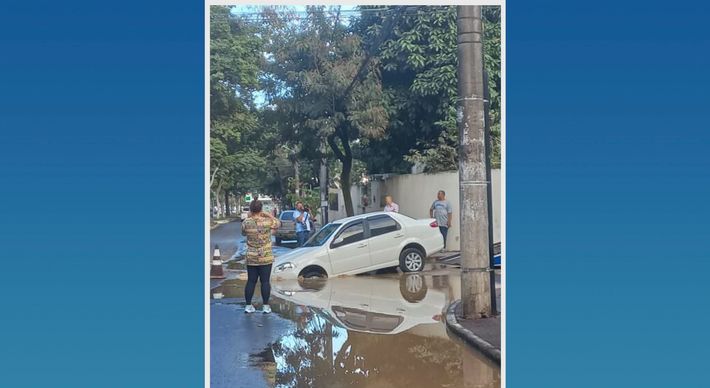 Buraco estava cheio de água e a parte da frente do automóvel afundou quando o veículo passava pelo local, atrapalhando o trânsito na via na manhã desta sexta-feira (12)