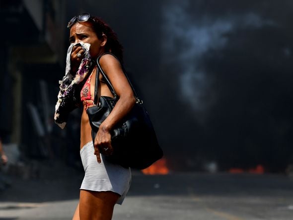 Fumaça faz com que moradora cubra o rosto. Foto: Fernando Madeira por Fernando Madeira