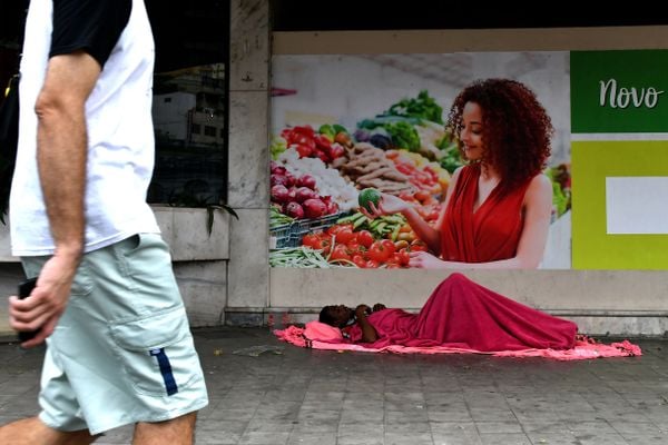 Homem em situação de rua dorme embaixo de propaganda de alimentos na calçada do Supermercado São José, Centro de Vitória