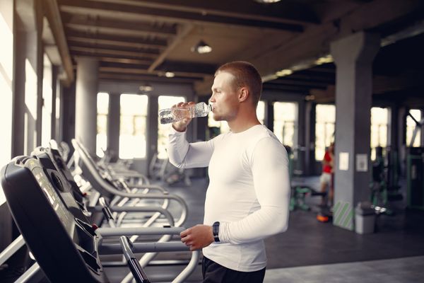 Sports man in the gym. A man on a racetrack. Guy in a white blouse.