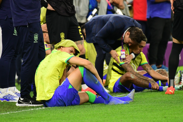 Aos prantos, jogadores sentam no meio do campo após eliminação. por Vitor Jubini