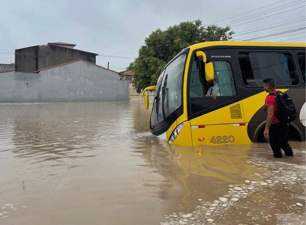 Ônibus cai em buraco de rua alagada após chuva em Guriri, São Mateus