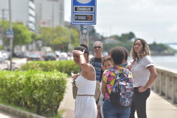 Pessoas esperando ônibus em ponto sem abrigo, Avenida Beira Mar, em Vitória