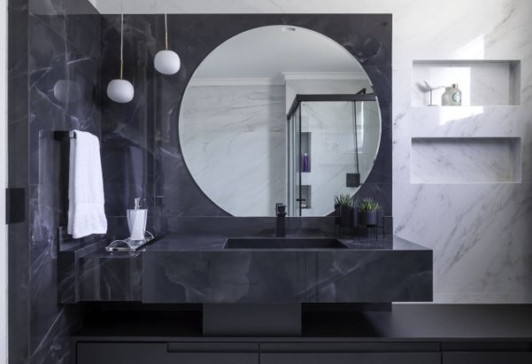 Elegância e sobriedade sintetizam o banheiro da suíte, que foi inspirado no mármore. O preto marca presença no porcelanato que reveste a área da bancada, incluindo a pia esculpida