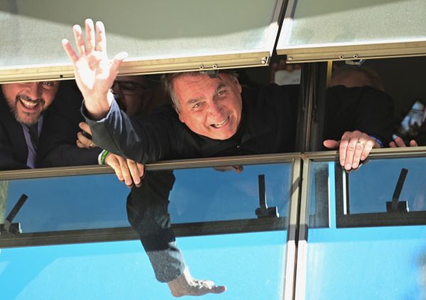 Ex-presidente Jair Bolsonaro acena para apoiadores pela janela do prédio onde fica a sede do PL em Brasília