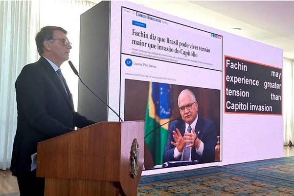 Bolsonaro durante pronunciamento a embaixadores; tela mostra notícia com tradução errada ao inglês 
