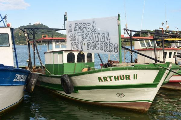 Barco com faixa de protesto que vai participar da procissão de São Pedro
