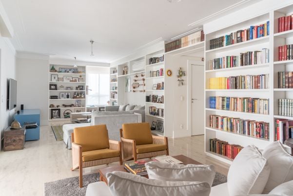 Em integração entre biblioteca e sala de estar, a arquiteta Isabella Nalon aproveitou a imensa coleção do morador para dispor os livros em uma ampla estante projetada por ela