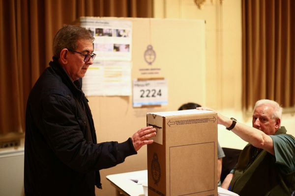 Eleitor deposita voto na urna em Buenos Aires, durante eleições para presidente na Argentina, neste domingo (22)