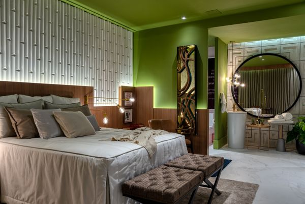 Na Suíte do Casal, Renzo Cerqueira apostou em tons verdes e materiais amadeirados no espaço, mas manteve as cores neutras na cama, no sofá e no tapete, por exemplo