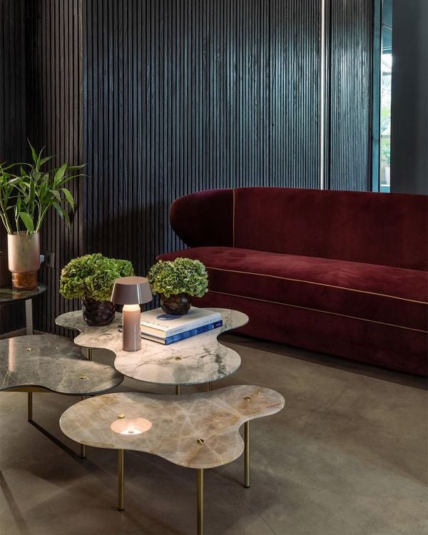 O projeto da sede do escritório de Vivian Coser exibe um mobiliário autoral feito com pedras naturais, que contrasta com as linhas sóbrias da arquitetura original do prédio