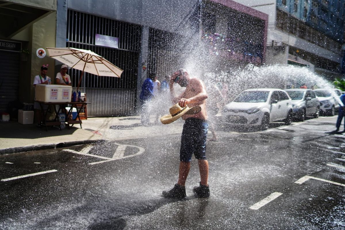 Calor na rua Gama Rosa. Foliões se refrescam com água de um carro pipa por Vitor Jubini