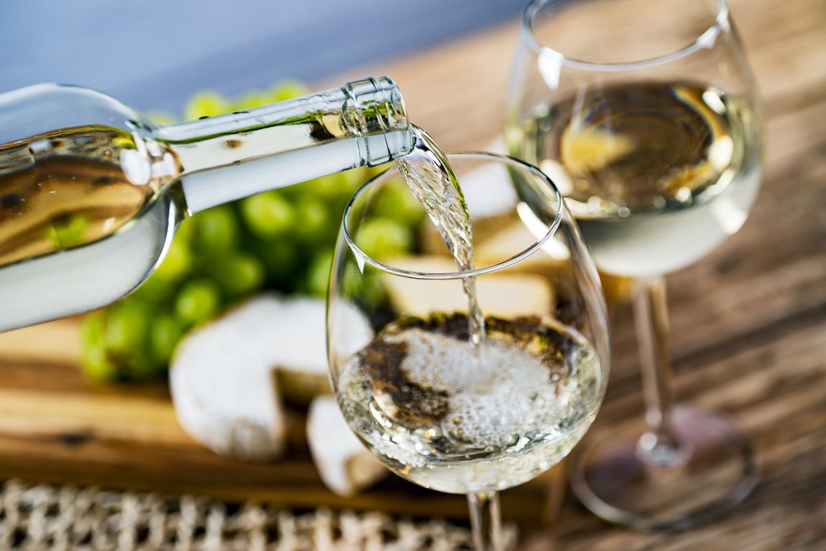Garrafa vertendo vinho branco na taça 