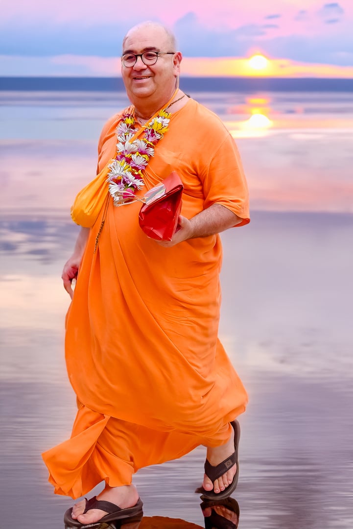 Chandramukha Swami caminhando à beira-mar ao pôr do sol