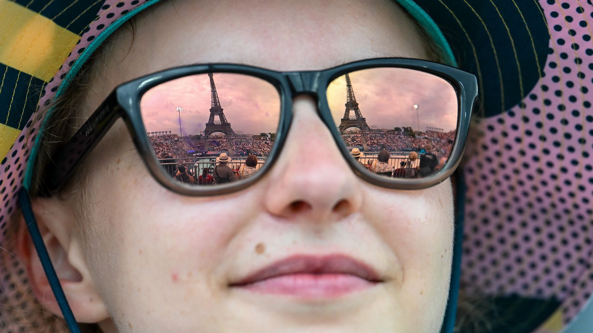 Stade Tour Eiffel refletido em óculos de voluntária nos jogos de Paris