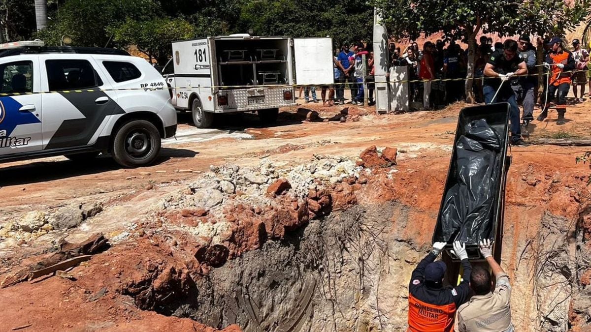 Foto mostra bombeiros retirando cadáver do local. 