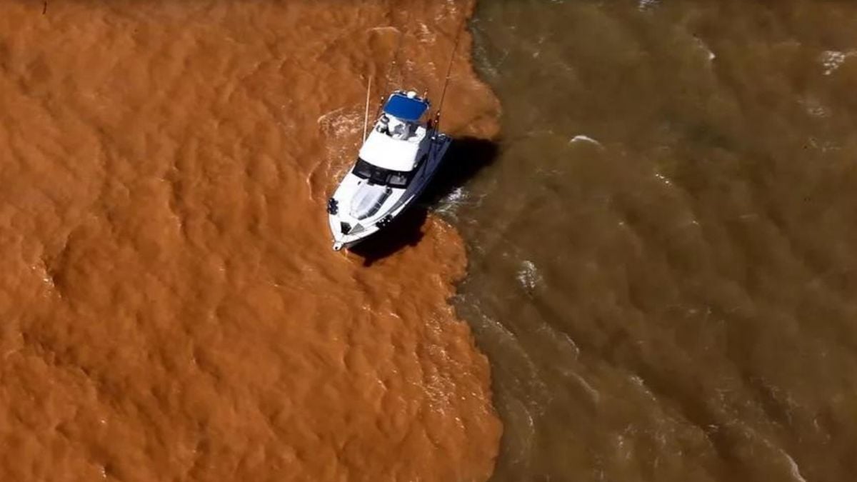 Barco passa por divisa entre lama e mar, em Regência, Linhares, Espírito Santo, em 2015