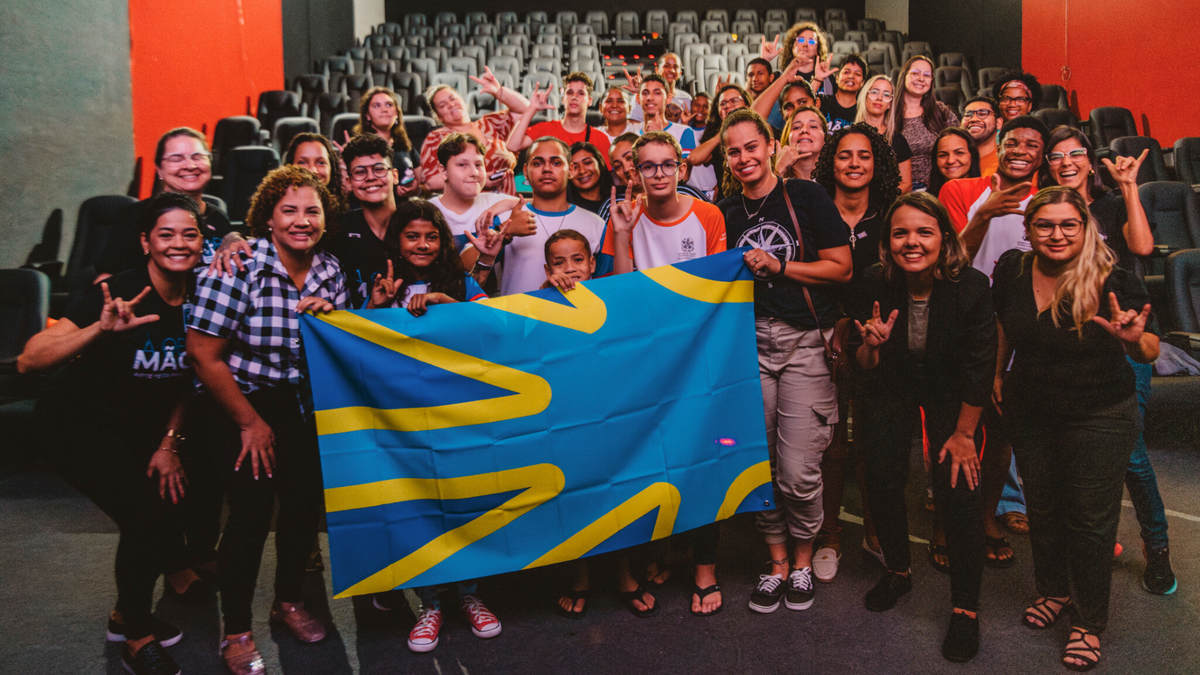 Equipe e telespectadores com a bandeira internacional da comunidade surda.