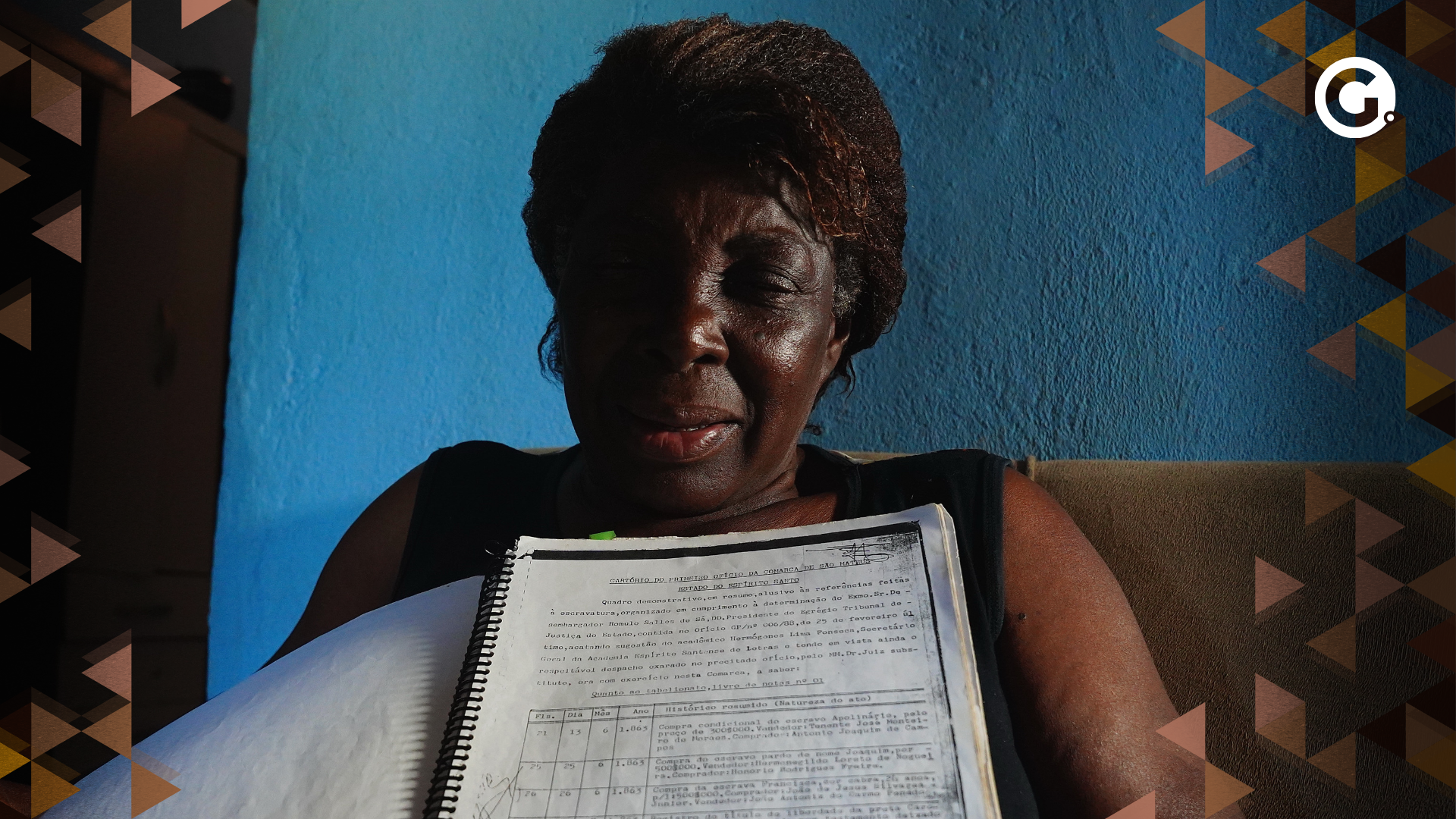 Elda Maria dos Santos, conhecida como dona Miúda, de 65 anos, segura livro com cópia de registro de venda de negros no Espírito Santo