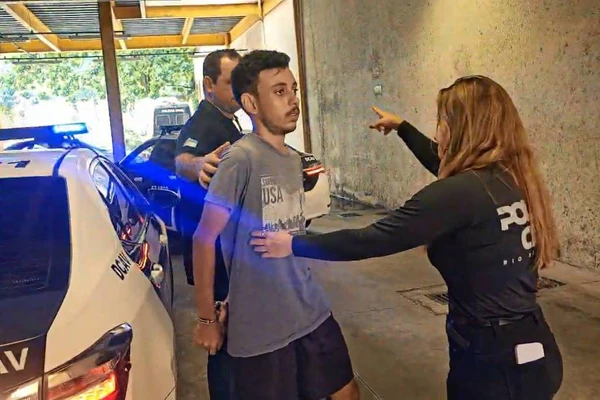 Bruce Vaz, 23, é conduzido por policiais após ser preso sob suspeita de comandar um canal no Discord que incitava crimes; grupo planejava matar um morador de rua no domingo de Páscoa 