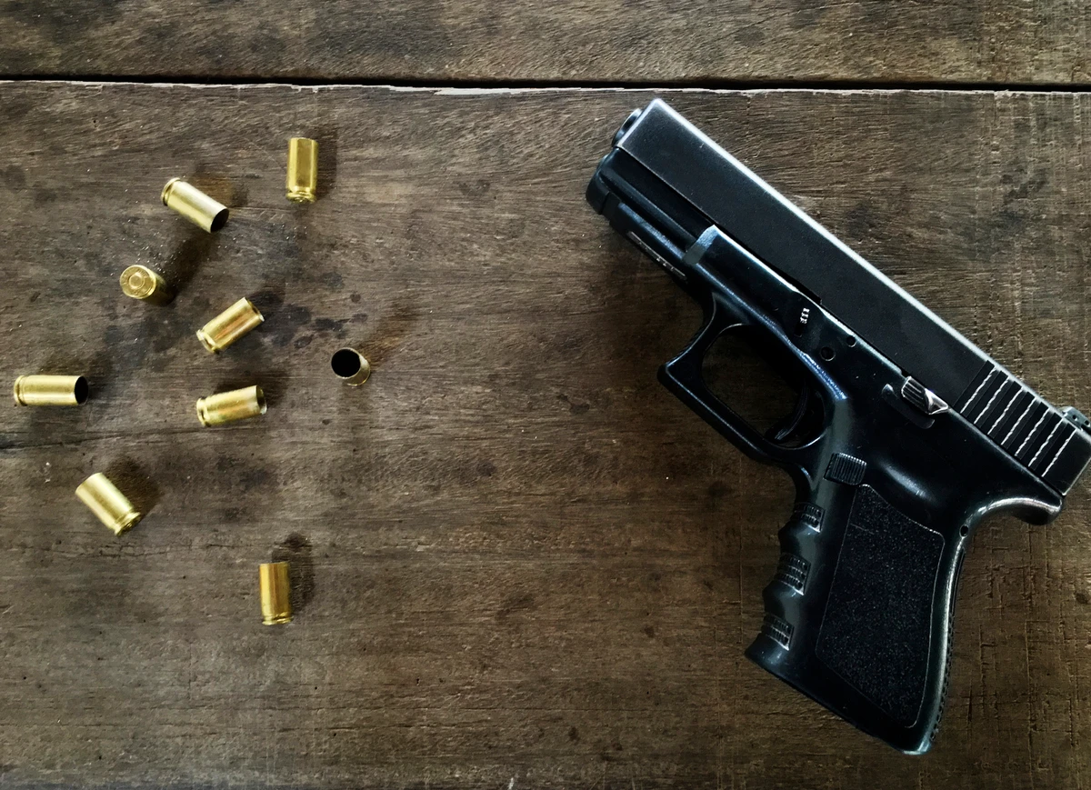 Pistola vazia com balas em cima de mesa