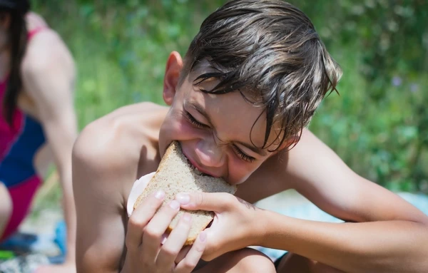 Criança comendo sanduíche na praia