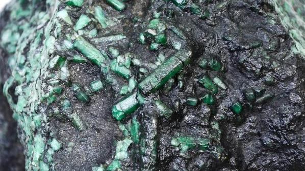 A peça é uma canga de esmeralda de formação rochosa com alta concentração de cristais hexagonais do tipo esmeralda, muitos deles bem preservados