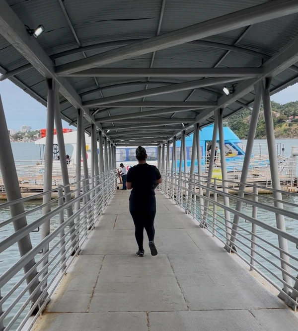 Pessoa de costas caminha por passarela para Aquaviário na Praça do Papa.